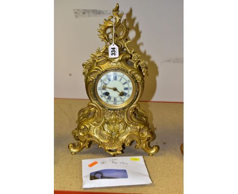 A LATE 19TH/EARLY 20TH CENTURY GILT METAL MANTEL CLOCK OF ROCOCO STYLE, scrolled finial with floral swags, the cream enamel d