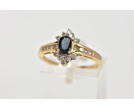 AN 18CT GOLD SAPPHIRE AND DIAMOND CLUSTER RING, centring on an oval cut blue sapphire, within a round brilliant cut diamond d