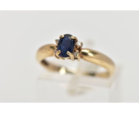 A 9CT GOLD SAPPHIRE AND DIAMOND RING, centring on an oval cut blue sapphire, flanked with four round brilliant cut diamonds, 