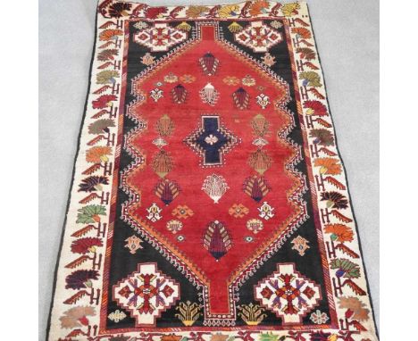 A Persian qashgai rug, with a central hooked medallion, within an ivory border, 205 x 120cm