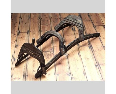 A middle eastern carved wood and metal mounted camel saddle, 130cm