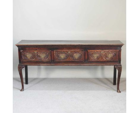 An 18th century oak dresser base, with later carved decoration, containing three short drawers, on cabriole legs184w x 50d x 