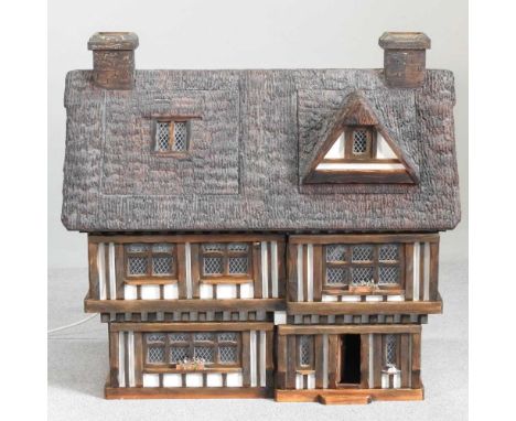 A doll's house by Robert Stubbs, 93cm wide, in the form of a thatched Tudor cottage, with a certificate of authenticity, toge