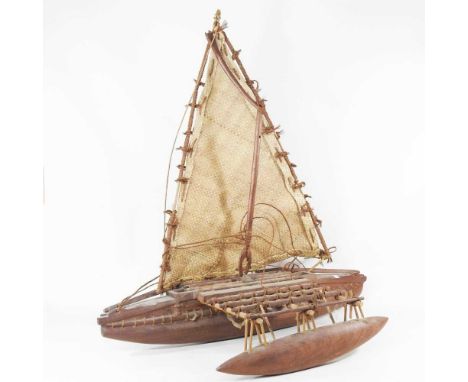 A carved wooden model of a Samoa canoe, with outrigger and woven sail, 84cm long