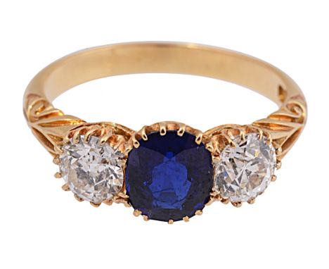 A sapphire and diamond three stone ring, the central circular mixed-cut sapphire set to either side with an old brilliant-cut