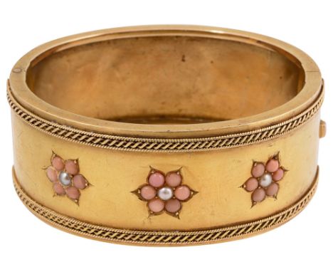 A Victorian yellow gold, coral and seed pearl hinged bangle the top section inlaid with three floral coral half bead and seed