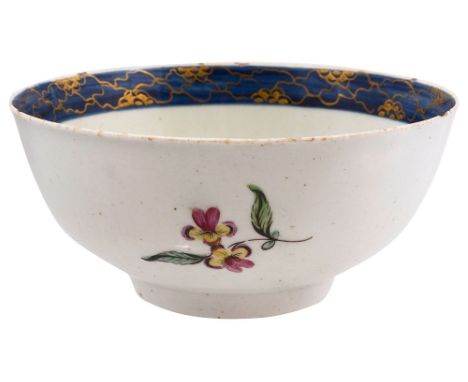 A late 18th century soft paste porcelain polychrome bowlpainted with a floral spray and scattered sprigs, interior with gilt 