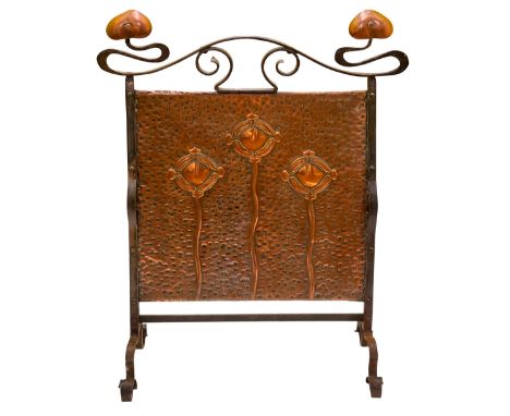An Arts &amp; Crafts wrought iron and copper firescreen the central rectangular hammered copper panel repouse embossed with s