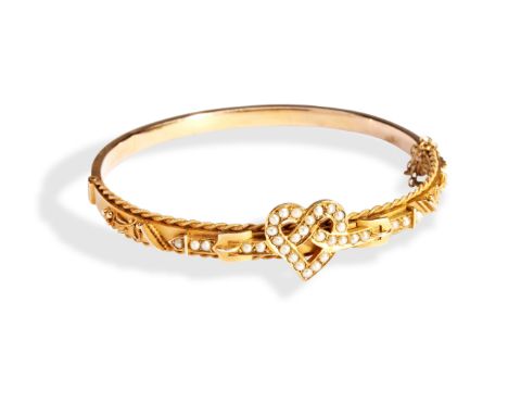 A VICTORIAN PEARL SET BANGLE the hinged bangle being set to the top with half seed pearls in a knotted heart motif between tw