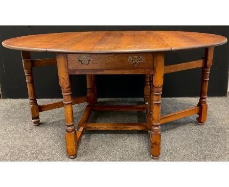 A Nigel Griffiths style large oak gate leg dining / kitchen table, oval top when leaves extended, single drawer to one end, t