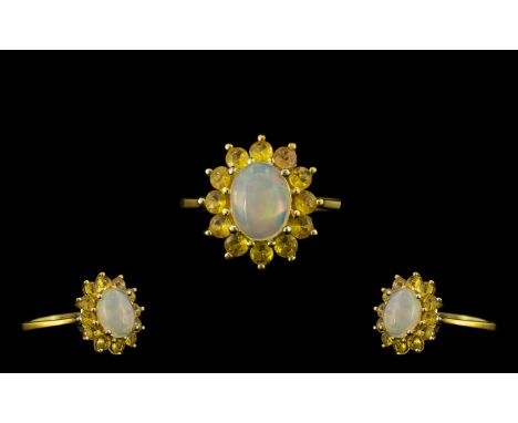 Opal and Yellow Sapphire Halo Ring, an oval cut cabochon opal of 1ct, framed by 1.25cts of round cut yellow sapphires; a clas