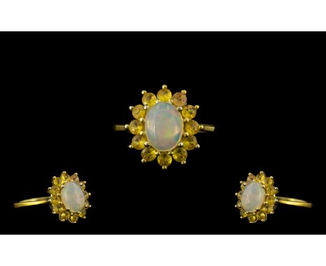 Opal and Yellow Sapphire Halo Ring, an oval cut cabochon opal of 1ct, framed by 1.25cts of round cut yellow sapphires; a clas