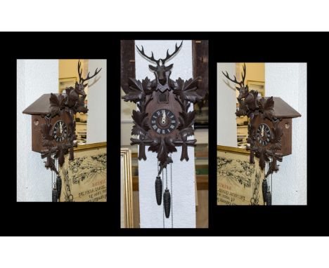 A Black Forest Cuckoo Clock, of typical form. With two weights and a stag and leaf pediment. Appears to be working but pendul