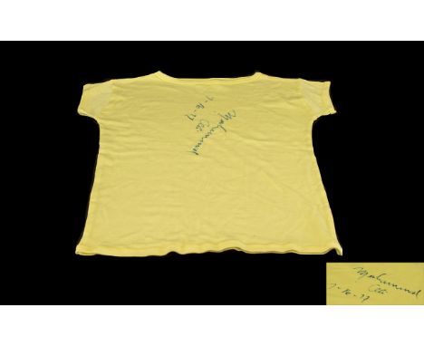 Mohammed Ali Signed 'T' Shirt.  Pale yellow 't' shirt signed with the autograph of Mohammed Ali, th famous boxer.  Dated 7-16