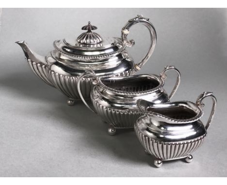 comprising: a teapot, a milk jug and a two-handled sugar basin, each rectangular body with gadrooning, applied with a leaf-ca