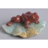 AN EARLY 20TH CENTURY CHINESE CARVED RED AGATE FROG ON A GREEN QUARTZ LILY PAD, 7cm wide.