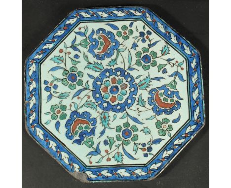AN ISLAMIC MARKET FRENCH OR ITALIAN GLAZED POTTERY OCTAGONAL TILE, painted with floral motifs, 23cm at widest point.