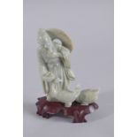A CHINESE CARVED JADEITE FIGURE ON HARDWOOD STAND, figure 13.5cm high.