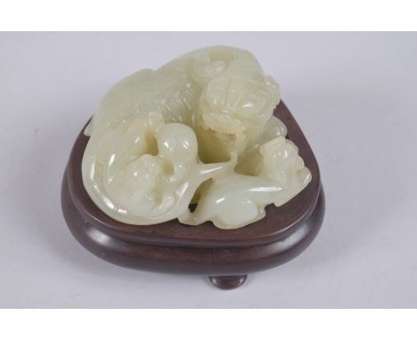 A CHINESE CARVED JADE LION GROUP ON HARDWOOD STAND, jade 9cm wide.