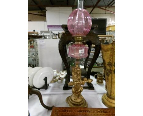An oil lamp with lion base, cranberry glass font and cranberry glass shade