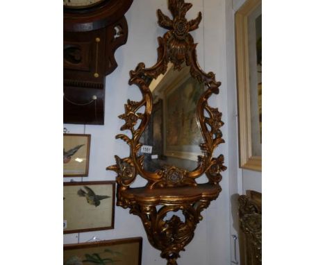 A gilt framed oval mirror with shelf