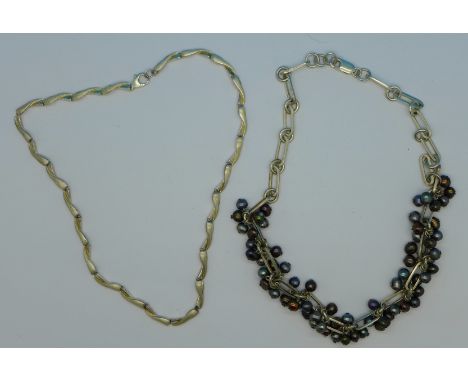 A silver necklace and a silver and black pearl necklace