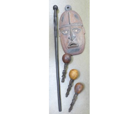 Three maracas with carved handles, a carved wooden African mask and an African carved hardwood fighting stick (5)