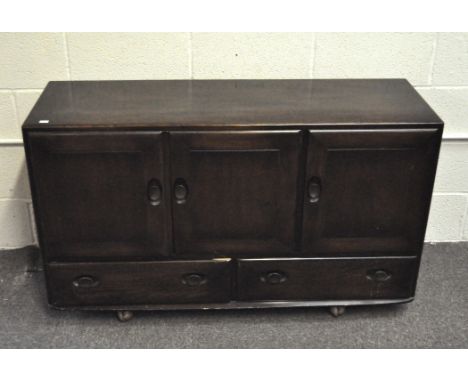 An Ercol dark stained elm Windsor sideboard, mid-century, having a pair of cupboard doors enclosing a shelf and a single cupb