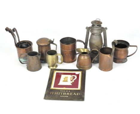 A collection of copper and brassware, including a group of tankards, three graduated measures, assorted jugs and an oil lamp