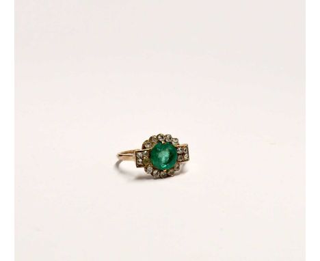 A yellow metal cluster ring set with central circular brilliant cut emerald in a surround of white stones, with Art Deco styl