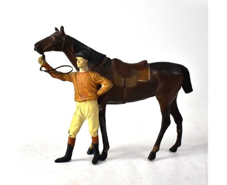 A painted metal model of a horse being held by its rider, the rider wearing brown jockey colours, unsigned.Height 10.5cmThere