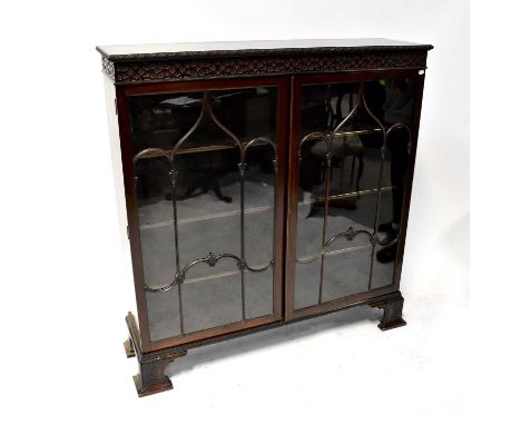 An Edwardian Chippendale-style mahogany glazed display cabinet with blind frieze and pair of doors enclosing shelves, on brac