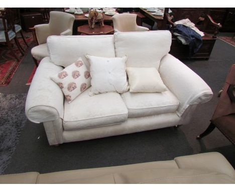 A white Laura Ashley sofa with Hedgehog cushions on front castors