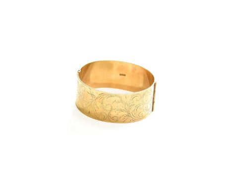 A 9 Carat Gold Hinged Bangle, decorated with scroll engraving, inner measurements 5.6cm by 5.2cmGross weight 45.7 grams.