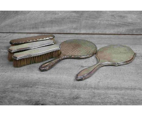 George V part silver dressing table brush set comprising hand mirror and two clothes brushes, each with engine turned reeded 