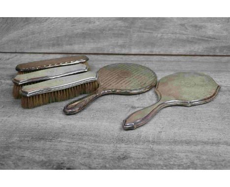 George V part silver dressing table brush set comprising hand mirror and two clothes brushes, each with engine turned reeded 