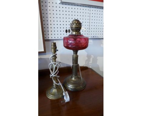 A 19th century oil lamp with cranberry glass shade together with a brass table lamp. 