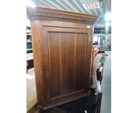 An early 19th Century oak corner wall cupboard having panel door