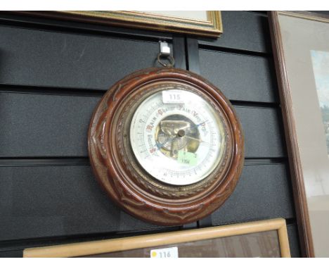A port hole design barometer with enamel face and carved oak body 