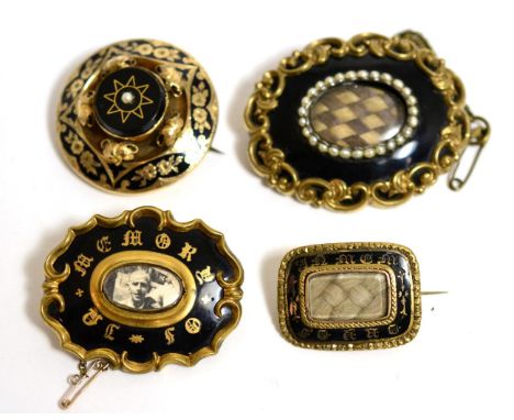 A group of four Victorian enamel and yellow metal mounted mourning brooches 