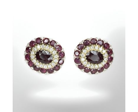 A pair of 14ct yellow gold ruby and diamond earrings featuring two oval cut rubies (1.29ct), claw set with twenty eight round