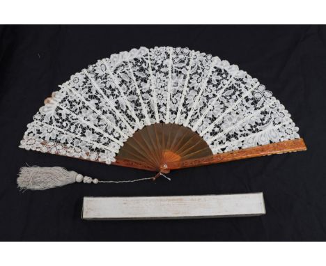 A Large Late 19th Century Brussels Bobbin Lace Fan, the guipure lace quite open with large flowers. Mounted on a sturdy amber