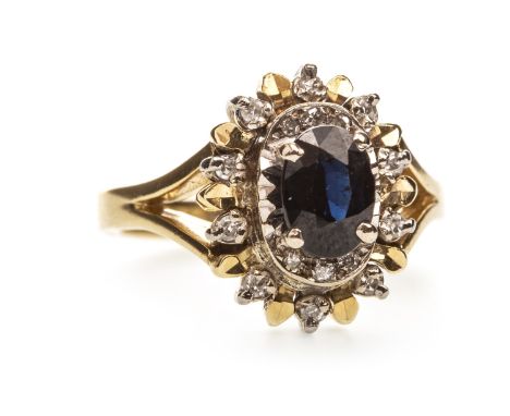 BLUE GEM AND DIAMOND CLUSTER RING, the oval blue gem surrounded by gold and diamond set sections, the round brilliant cut dia