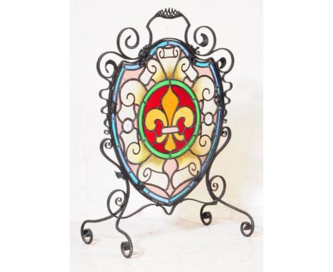 A 19th Century Victorian stained glass fireguard with wrought iron detailing and decoration in an escutcheon shape with fleur