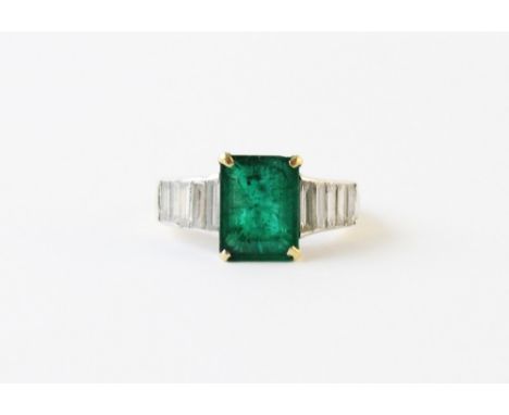 An emerald and diamond ring, the central step cut emerald weighing approx. 3.15 carats, measuring 10.52mm L x 8.06mm W x 5mm 