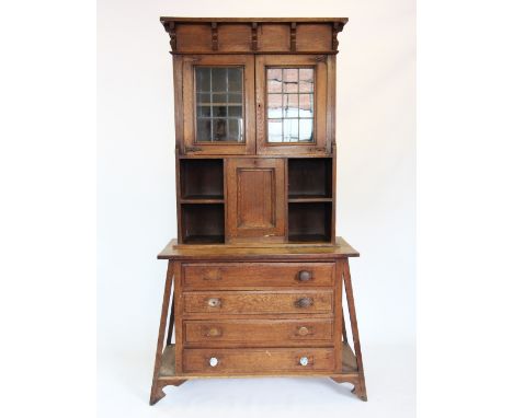 A Glasgow school Arts and Crafts oak cabinet on chest, circa 1900, the hinged flat top and frieze concealing a vacant compart