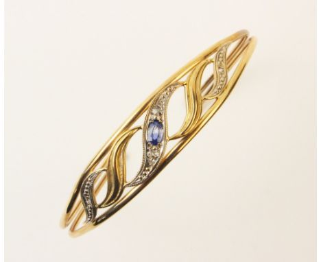 A 9ct gold sapphire and diamond set bangle, the central pierced scrolling panel set with an oval mixed cut sapphire and small