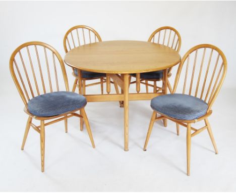 An Ercol light elm 'Golden dawn' windsor drop leaf kitchen table and chairs, the oval drop leaf table on twin spreading suppo