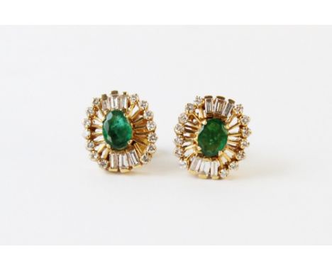 A pair of emerald and diamond cluster earrings, each comprising an oval faceted emerald measuring 6.1mm x 4.6mm, with a clust