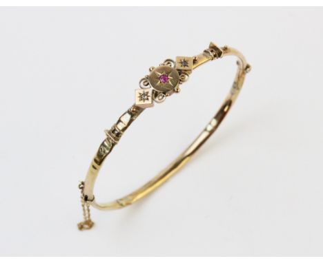 A Victorian diamond and ruby set bangle, the central panel set with a small mixed cut ruby and two small eight cut diamonds, 
